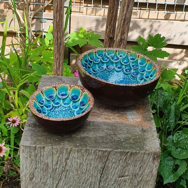Handgemaakte halve bollen van keramiek met een rijkelijke bewerking in een mooie blauwe kleur geglazuurd. Randen en buitenkant van de bollen zijn voorzien van een bronskleurige glazuur.